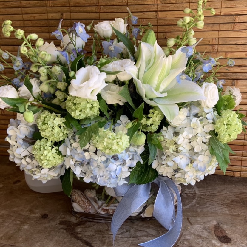 White hydrangea, lily, and delphinium arrangement with ribbon