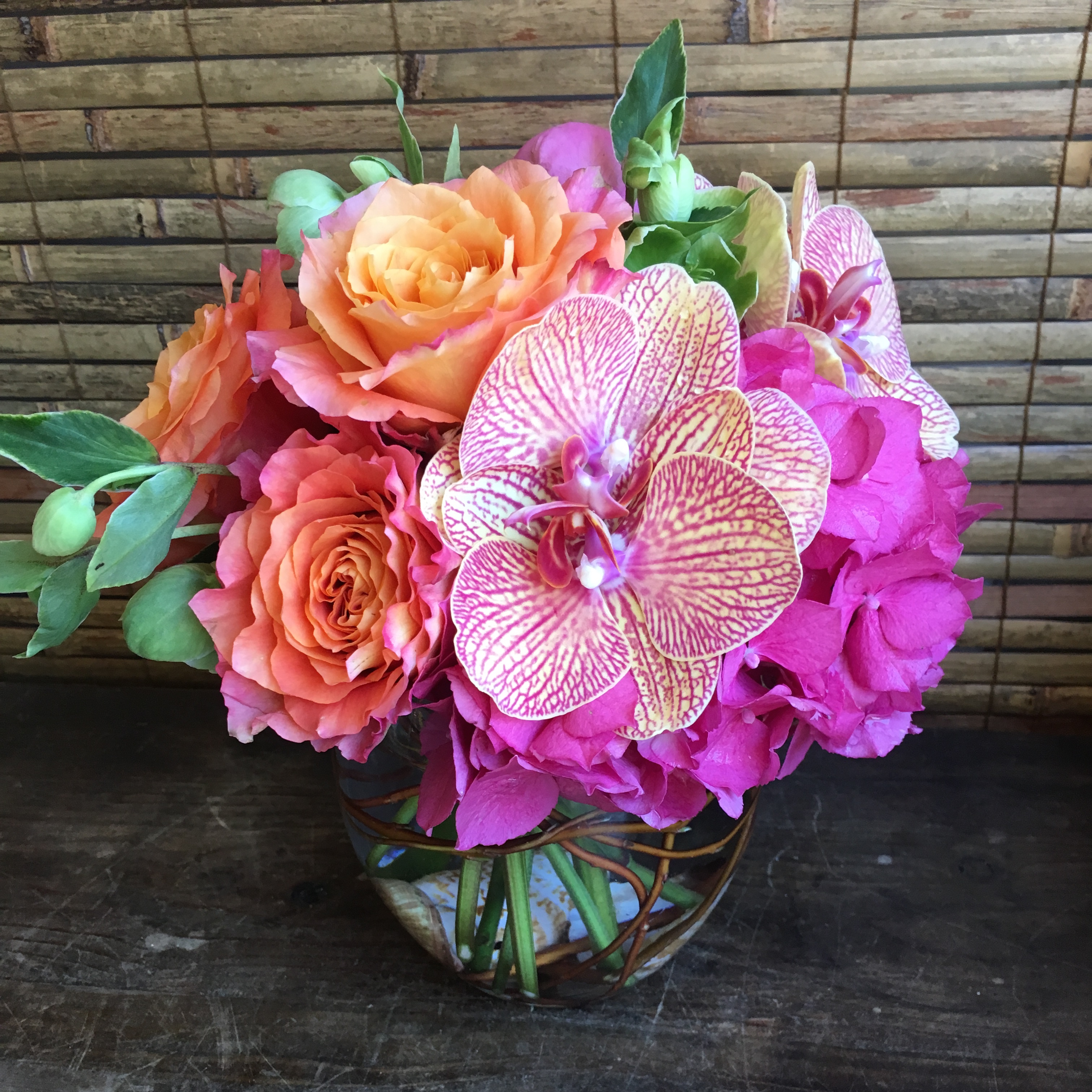 Coral rose, phalaenopsis orchid, and fuchsia peony arrangement